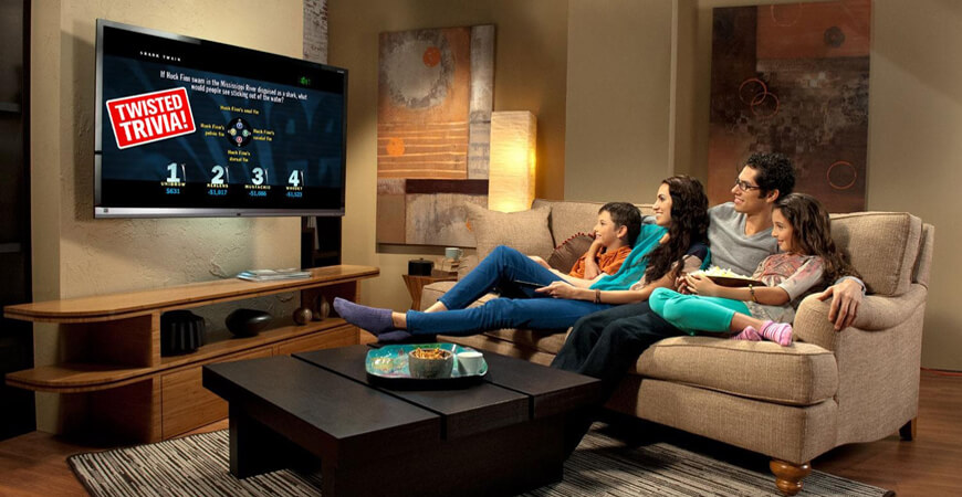 Two women sitting on a couch watching television.